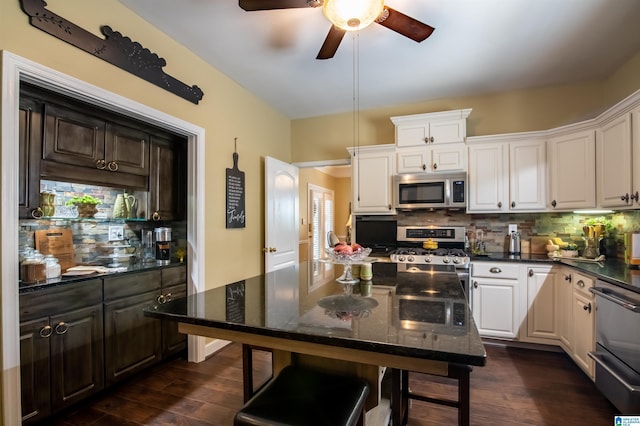 kitchen with appliances with stainless steel finishes, backsplash, dark hardwood / wood-style floors, and white cabinetry