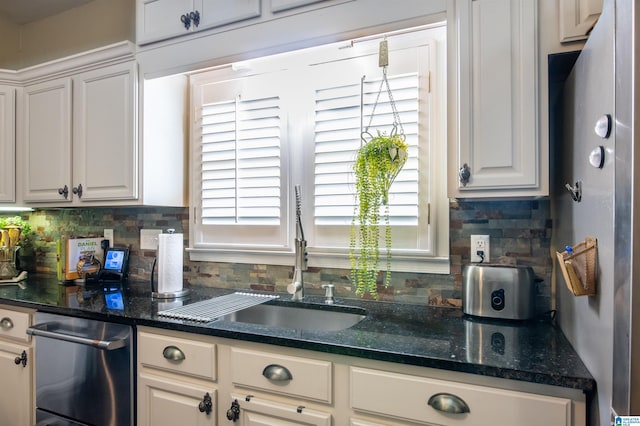 kitchen with decorative backsplash, white cabinetry, dark stone counters, and sink