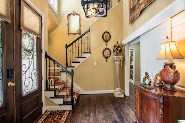 entryway featuring a towering ceiling, an inviting chandelier, and dark wood-type flooring