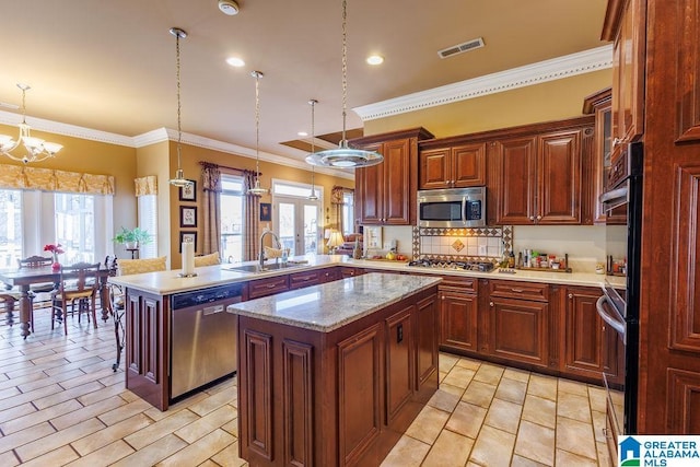 kitchen featuring kitchen peninsula, stainless steel appliances, sink, pendant lighting, and a center island