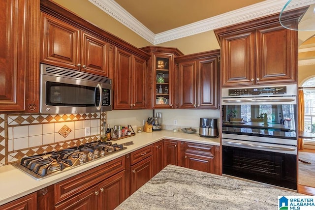 kitchen featuring light stone countertops, ornamental molding, and appliances with stainless steel finishes