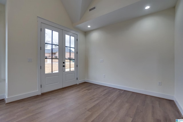 doorway with vaulted ceiling, light wood-type flooring, and french doors