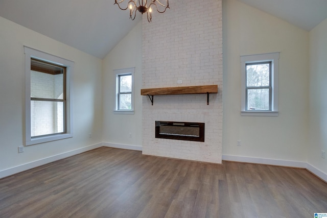 unfurnished living room featuring hardwood / wood-style flooring, a notable chandelier, a healthy amount of sunlight, and a fireplace