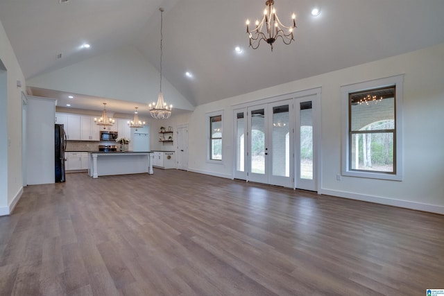 unfurnished living room with french doors, light hardwood / wood-style floors, and high vaulted ceiling