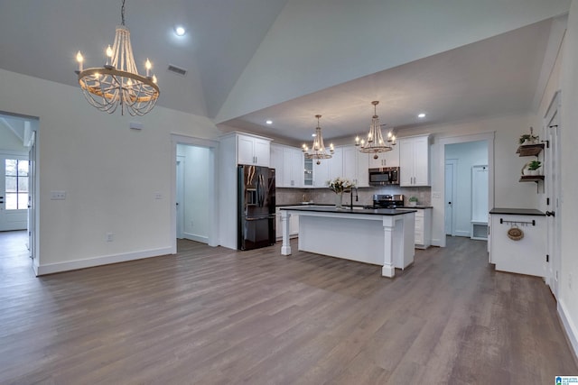 kitchen featuring hanging light fixtures, tasteful backsplash, a kitchen island with sink, white cabinets, and appliances with stainless steel finishes