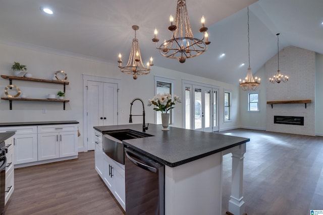 kitchen with a fireplace, sink, white cabinets, and a center island with sink