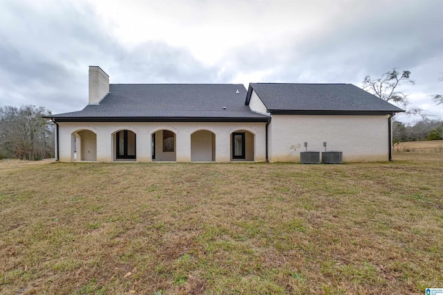 rear view of property featuring a yard and central AC unit