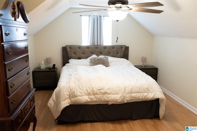 bedroom with wood-type flooring, a textured ceiling, vaulted ceiling, and ceiling fan