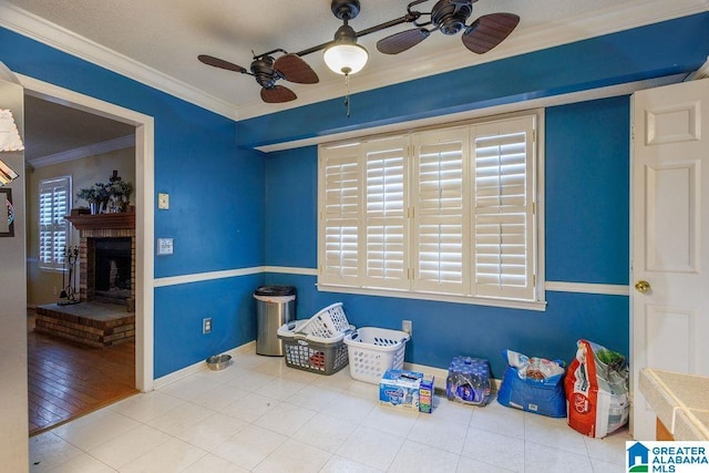 recreation room featuring tile patterned flooring, ceiling fan, ornamental molding, and a fireplace