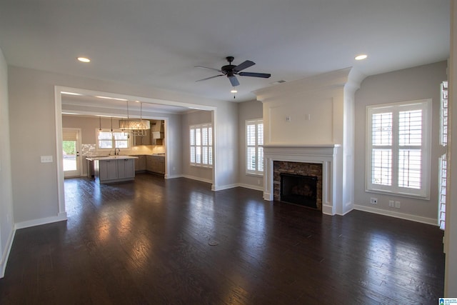 unfurnished living room with a premium fireplace, dark hardwood / wood-style flooring, and ceiling fan with notable chandelier