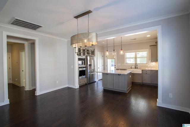 kitchen with appliances with stainless steel finishes, backsplash, gray cabinetry, pendant lighting, and a center island