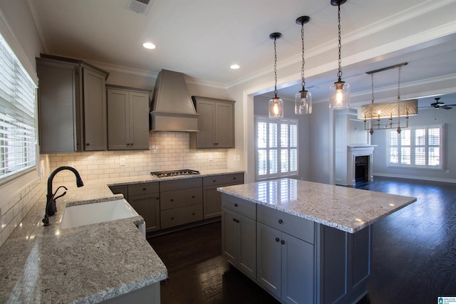 kitchen featuring ceiling fan, sink, pendant lighting, stainless steel gas stovetop, and custom exhaust hood