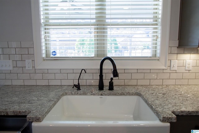 details featuring tasteful backsplash, light stone counters, and sink