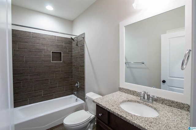 full bathroom featuring vanity, tiled shower / bath combo, and toilet