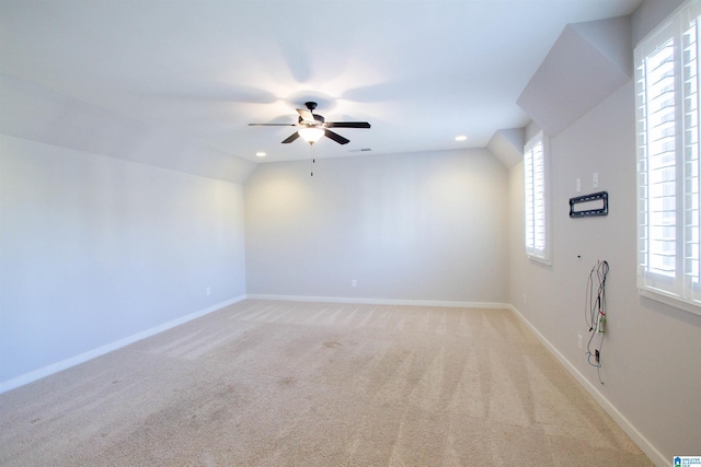 carpeted spare room featuring ceiling fan and vaulted ceiling