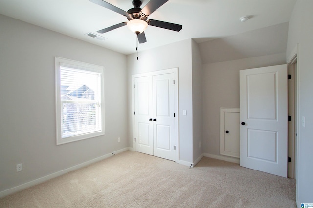 unfurnished bedroom with ceiling fan, light colored carpet, and a closet