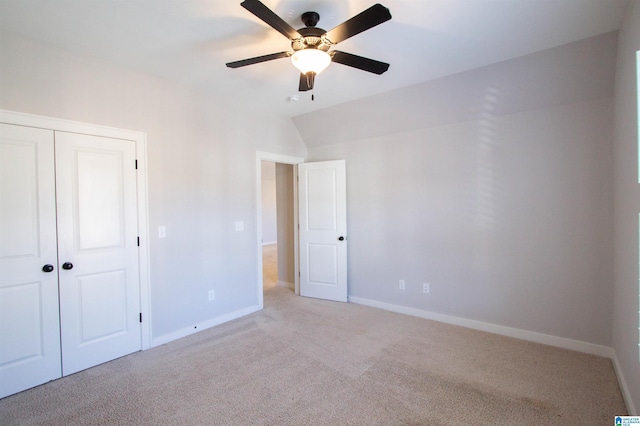 unfurnished bedroom with ceiling fan, a closet, light carpet, and vaulted ceiling