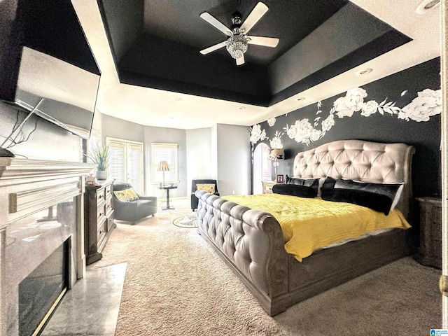 carpeted bedroom featuring a raised ceiling and ceiling fan