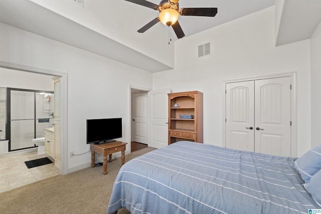 carpeted bedroom with ensuite bath, a closet, and ceiling fan