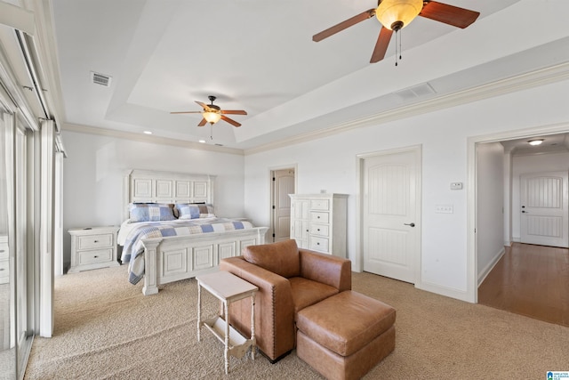 bedroom with ceiling fan, a tray ceiling, crown molding, and light colored carpet