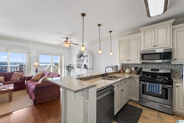 kitchen featuring kitchen peninsula, light stone countertops, pendant lighting, stainless steel appliances, and sink