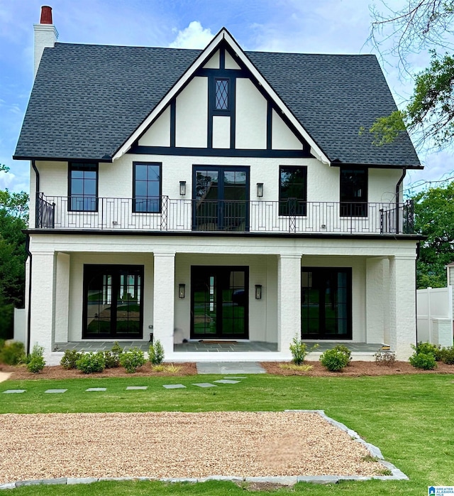 back of house with a lawn, covered porch, and a balcony