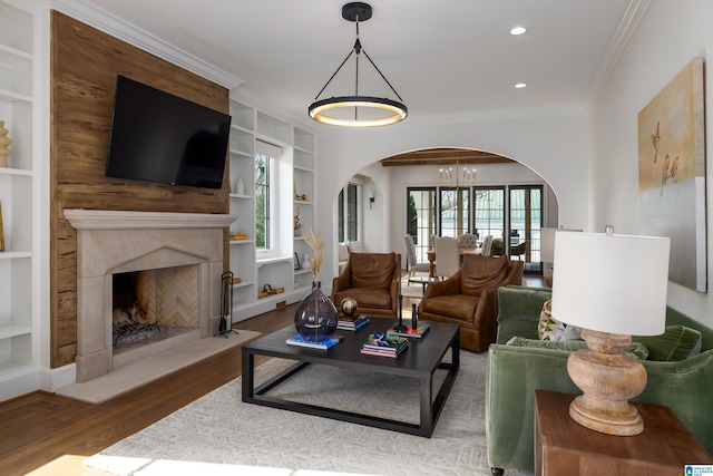 living room with a notable chandelier, ornamental molding, hardwood / wood-style floors, and built in features