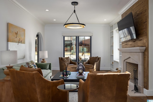 living room featuring a fireplace, built in shelves, crown molding, and light hardwood / wood-style flooring