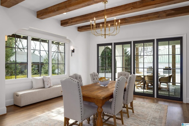 dining room with beam ceiling, light hardwood / wood-style flooring, and a chandelier