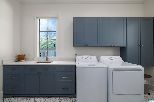 clothes washing area with sink, washer and dryer, crown molding, and cabinets