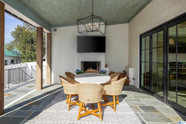 sunroom / solarium featuring french doors, an inviting chandelier, wooden ceiling, and an outdoor brick fireplace