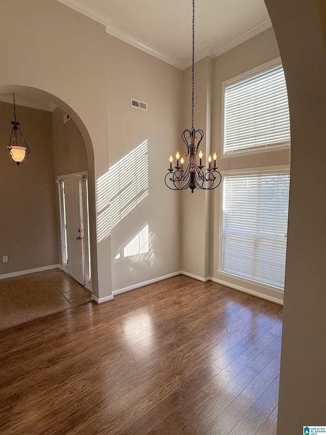 spare room featuring dark hardwood / wood-style flooring, ornamental molding, and a chandelier