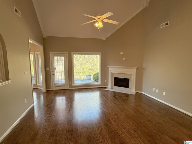 unfurnished living room with high vaulted ceiling, crown molding, ceiling fan, dark hardwood / wood-style floors, and a tiled fireplace