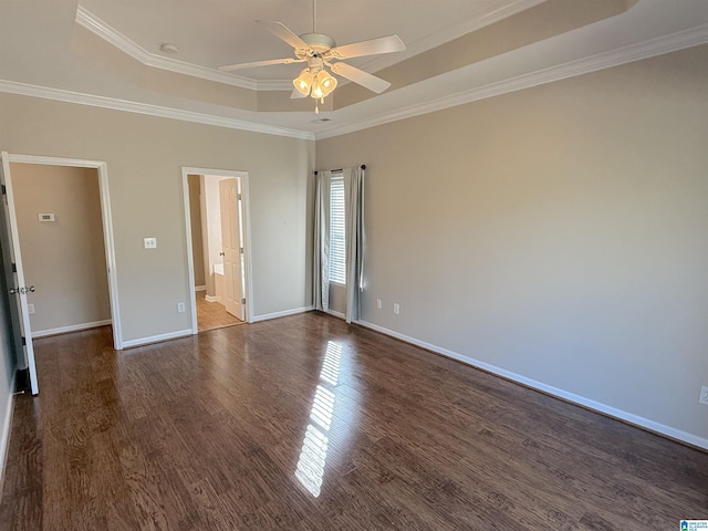 unfurnished room featuring a raised ceiling, crown molding, and dark wood-type flooring