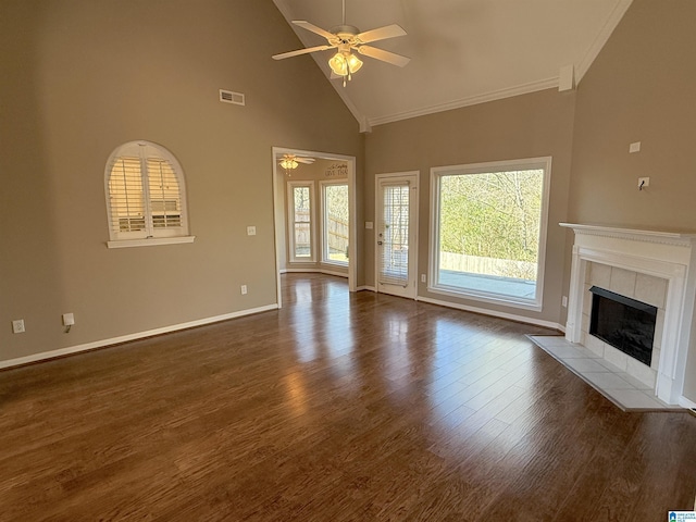 unfurnished living room with ceiling fan, dark wood-type flooring, high vaulted ceiling, crown molding, and a fireplace