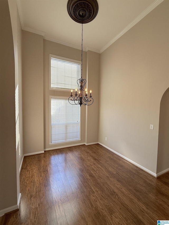 unfurnished dining area featuring a chandelier, dark wood-type flooring, and ornamental molding