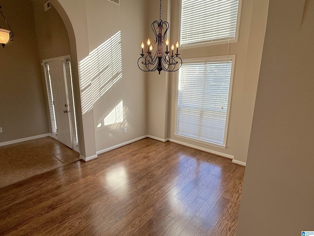 spare room with hardwood / wood-style flooring and an inviting chandelier