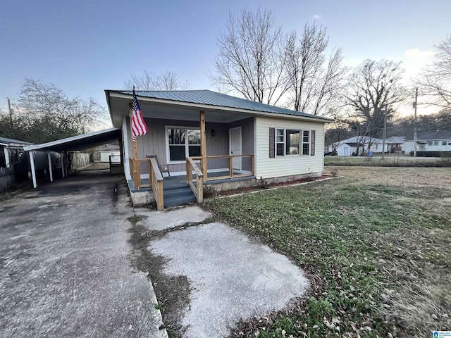 view of front facade featuring a carport, a porch, and a yard