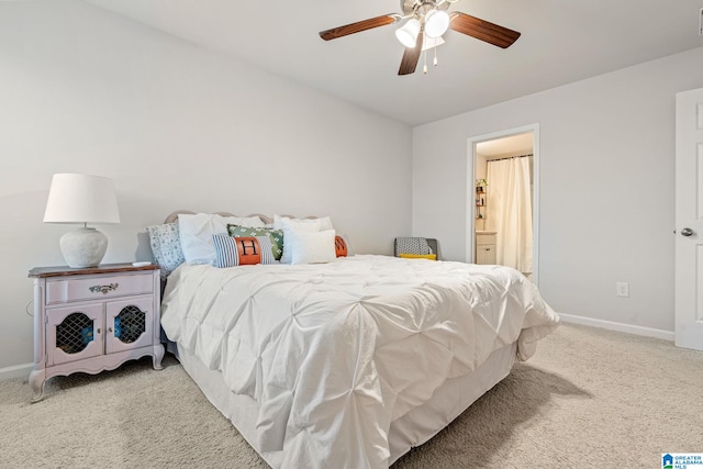 bedroom featuring light colored carpet, ensuite bath, and ceiling fan