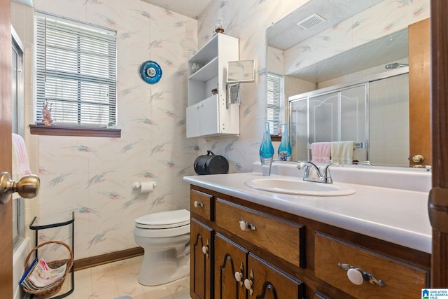 bathroom with vanity, toilet, and a shower with door