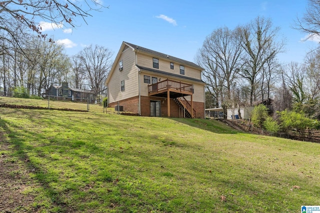 rear view of house with a wooden deck, a yard, cooling unit, and a trampoline