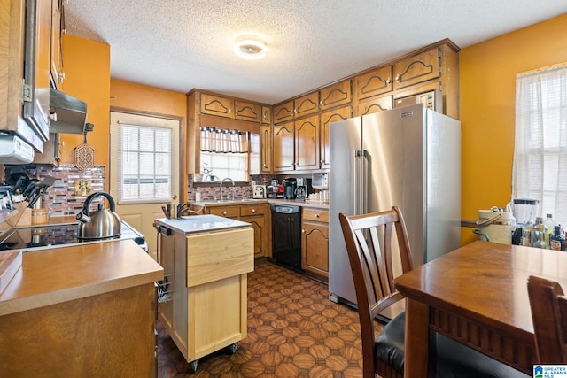 kitchen featuring dishwasher, a center island, high end refrigerator, stove, and a textured ceiling