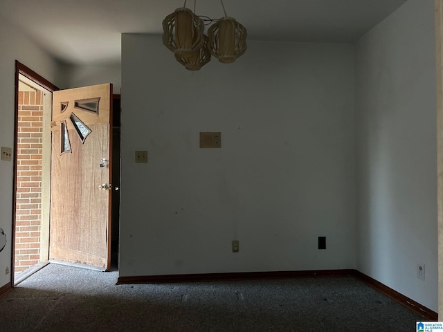 carpeted spare room with an inviting chandelier