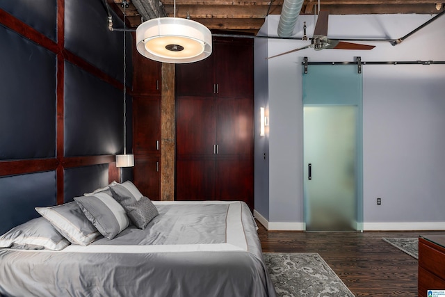 bedroom with dark hardwood / wood-style floors and a barn door