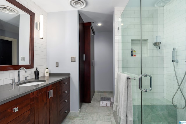 bathroom featuring a shower with shower door, vanity, and decorative backsplash