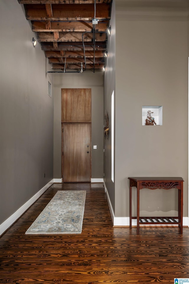 foyer entrance with dark wood-type flooring and beamed ceiling