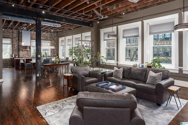 living room with dark wood-type flooring and brick wall