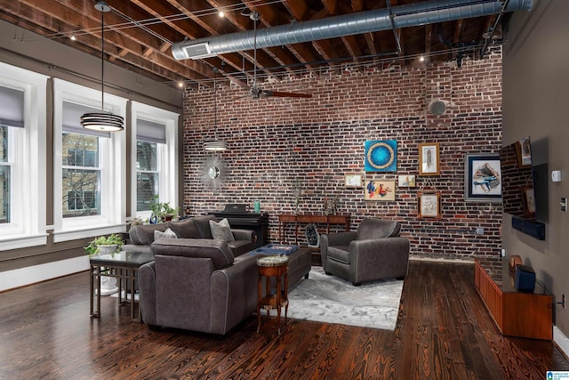 living room featuring ceiling fan, a towering ceiling, track lighting, dark hardwood / wood-style flooring, and brick wall