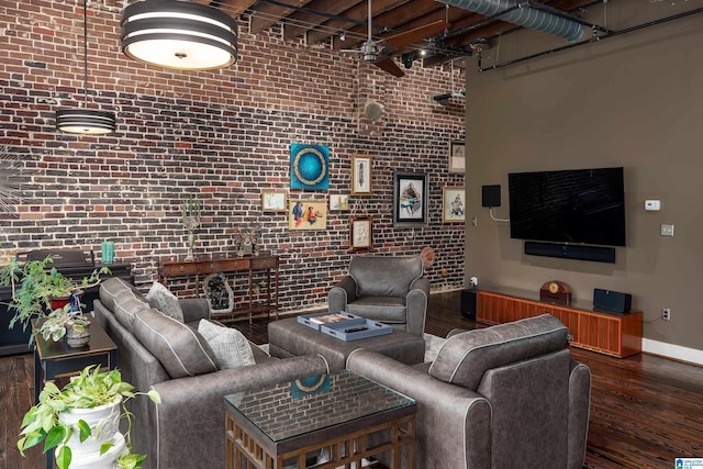 living room featuring dark hardwood / wood-style floors, brick wall, and a towering ceiling