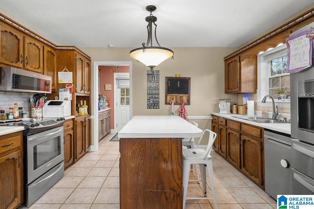 kitchen featuring pendant lighting, sink, appliances with stainless steel finishes, tasteful backsplash, and a kitchen island